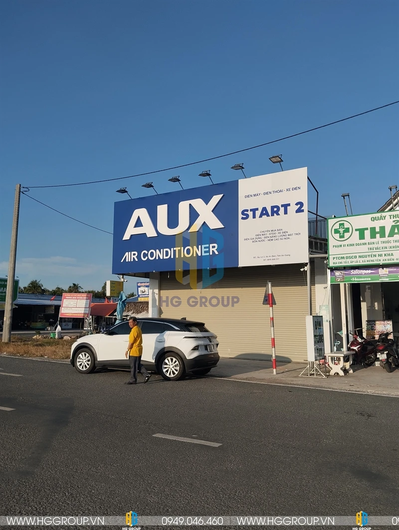 Biển quảng cáo pano ngoài trời tấm lớn: Biển hiệu nổi bật với nền xanh dương đậm, chữ nổi màu trắng quảng cáo cho hãng "AUX AIR CONDITIONER"
